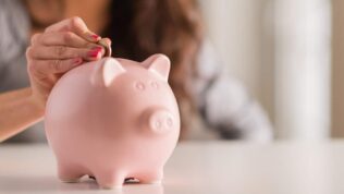 Person putting coins into a piggy bank to save for a rainy day